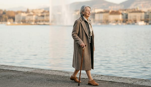 Une dame âgée marche élégamment au bord du lac Léman, canne à la main